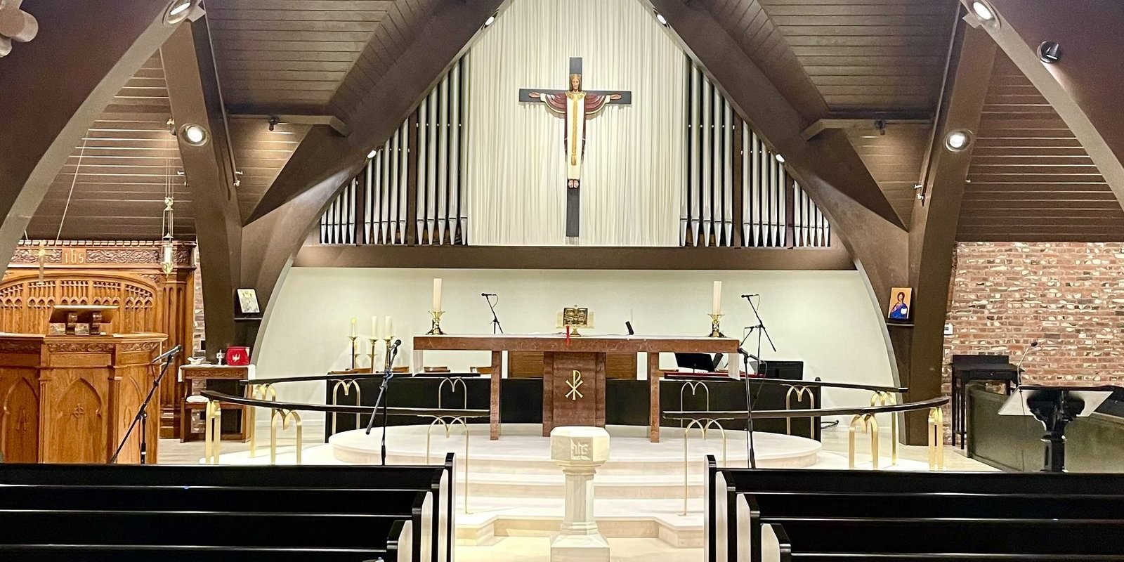 All Saints chancel after remodeling with pale flooring, curved railings and dark pews along the aisle