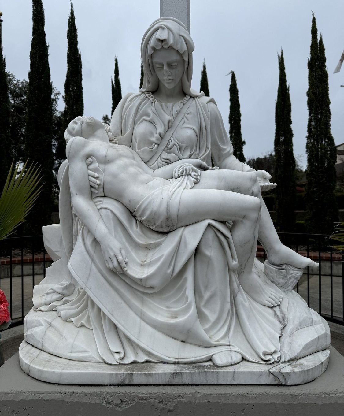 Outdoor Pietà showing Mary holding Jesus on a pedestal before restoration.