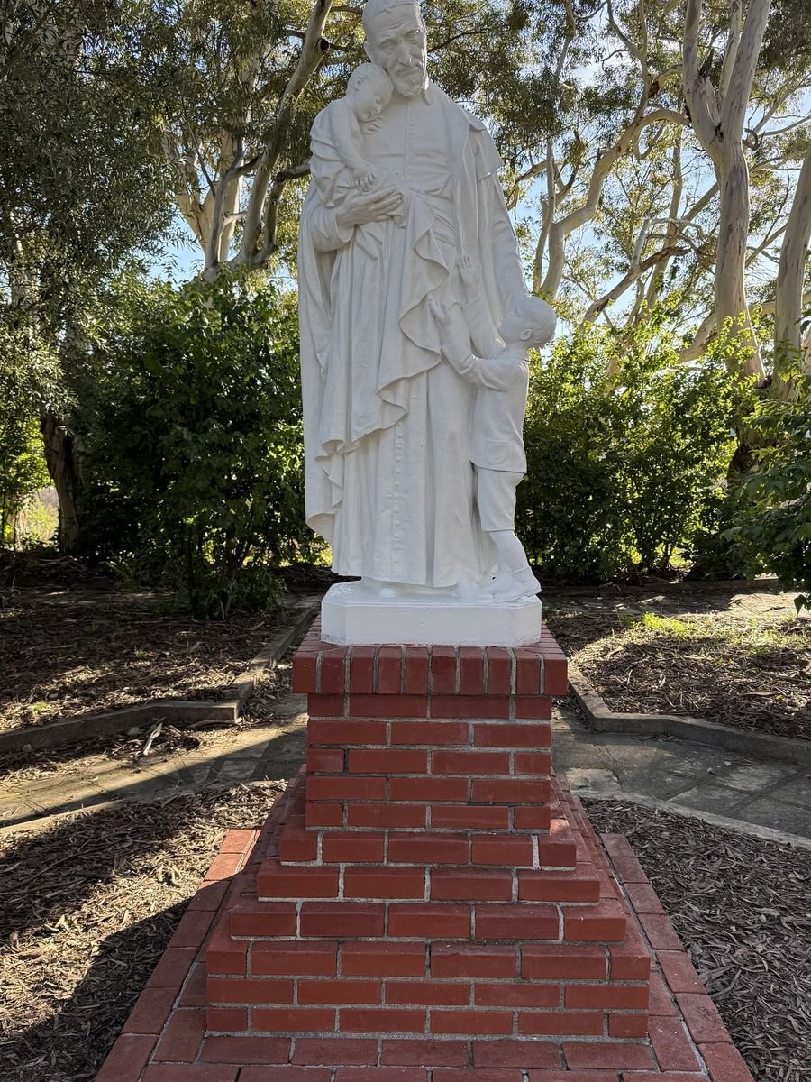 Restored standing group with two children on a brick pedestal among trees.