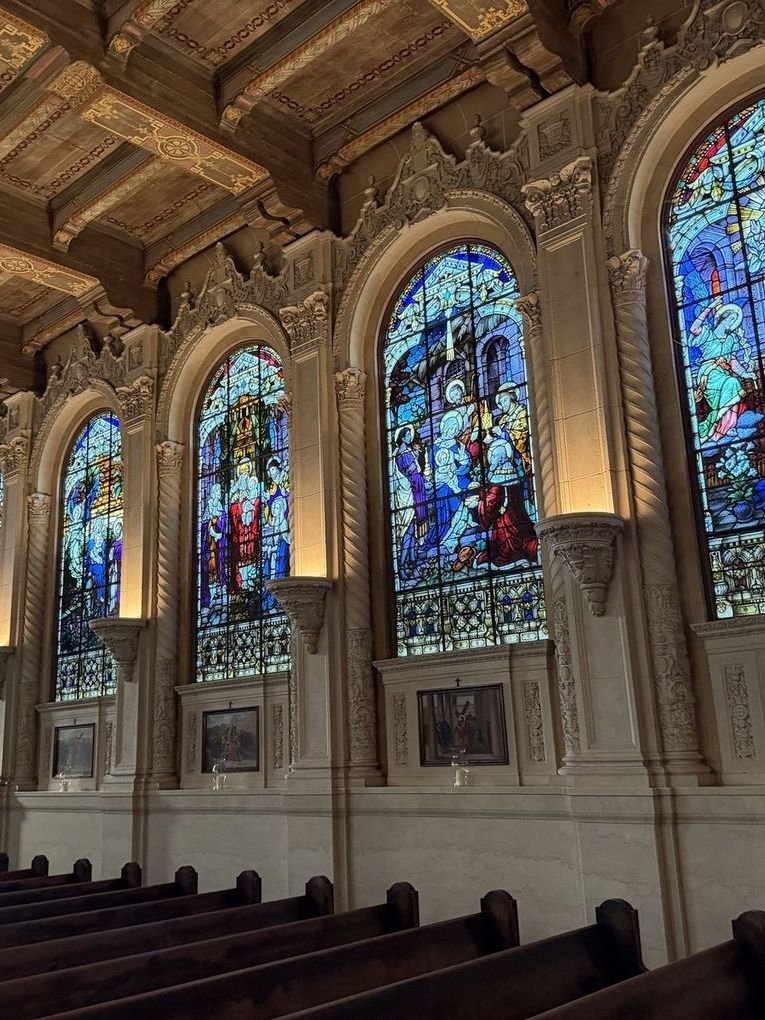A row of arched stained glass windows with carved surrounds above the pews at Saint Vincent Church