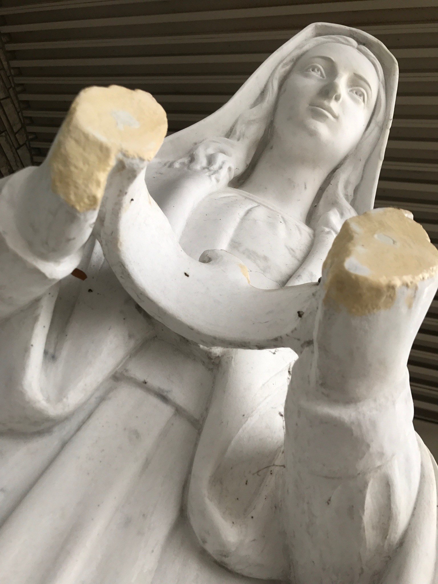 Close view of a marble figure with both forearms broken off.