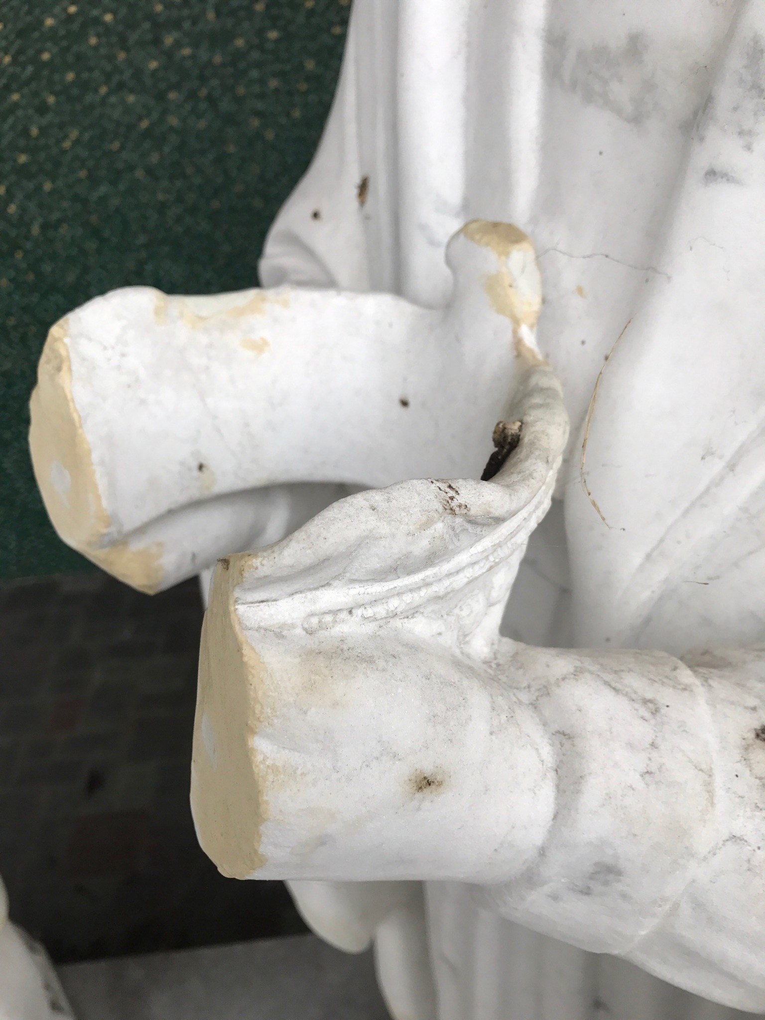 Close view of the damaged hands and crown in the marble group.
