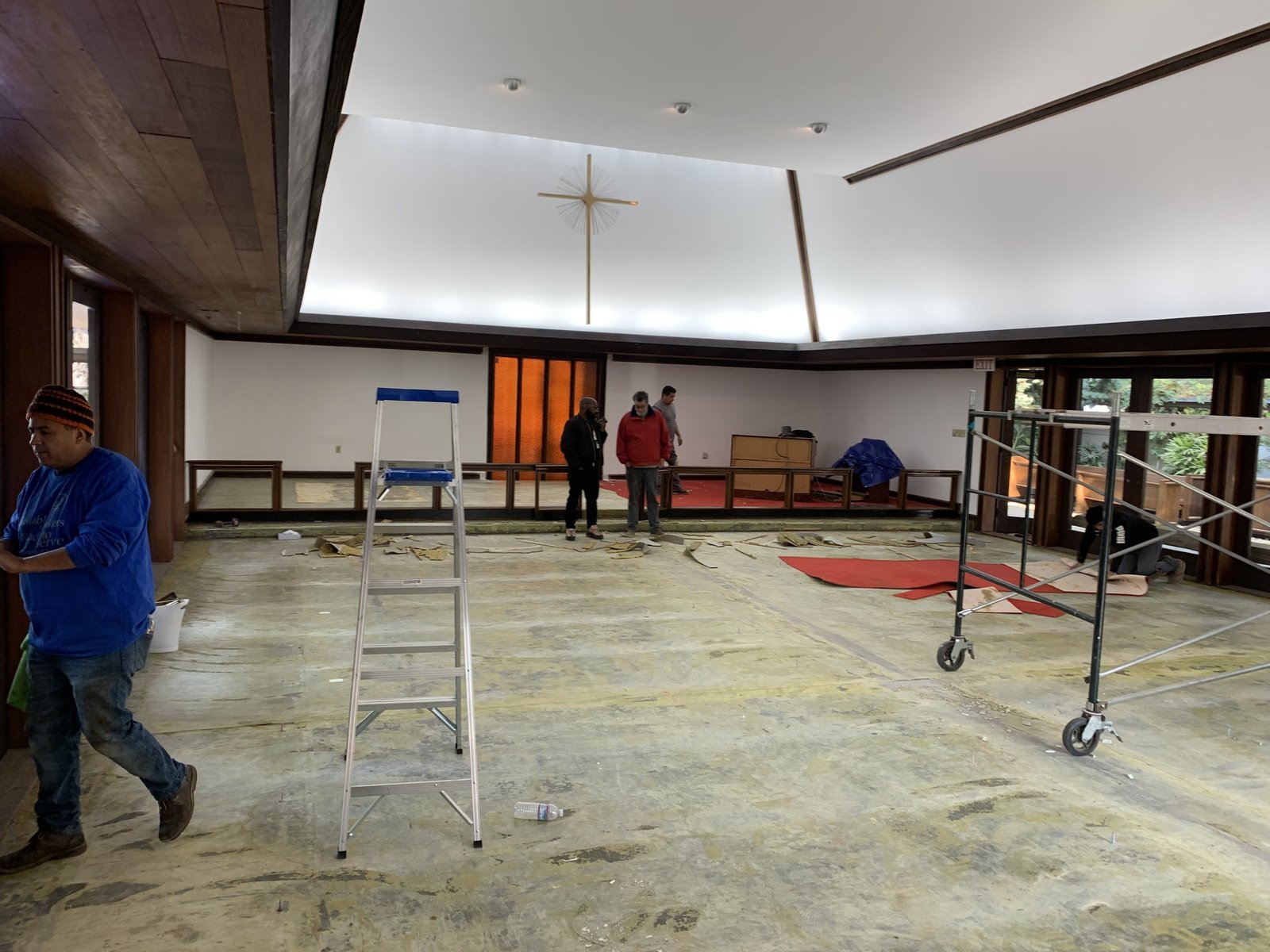 Open center floor of the church with a ladder, scaffolding and pews along the sides