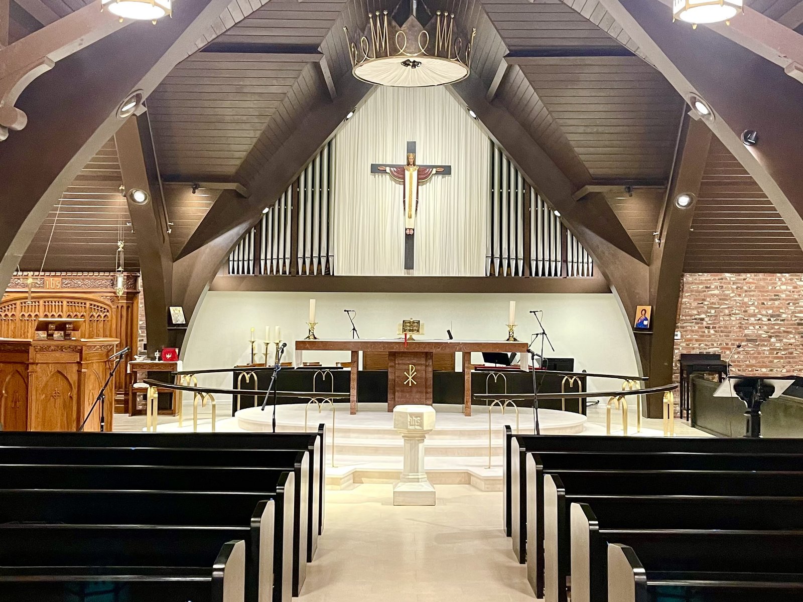 All Saints chancel after remodeling with pale flooring, curved railings and dark pews along the aisle