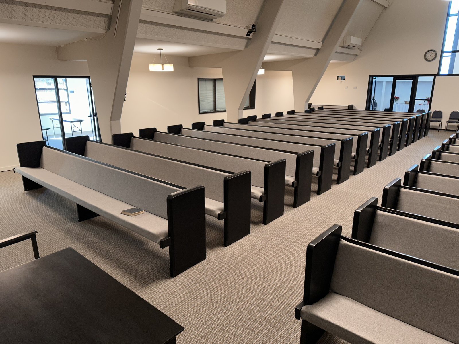 Rows of pews with gray seats and backs and dark end panels viewed from the side