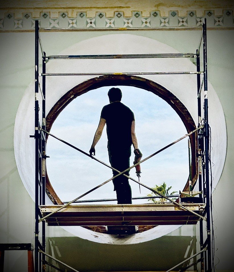 Worker on scaffolding at the empty round window opening.