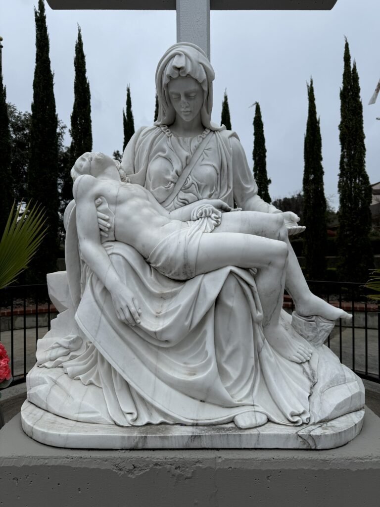 Outdoor Pietà showing Mary holding Jesus on a pedestal before restoration.