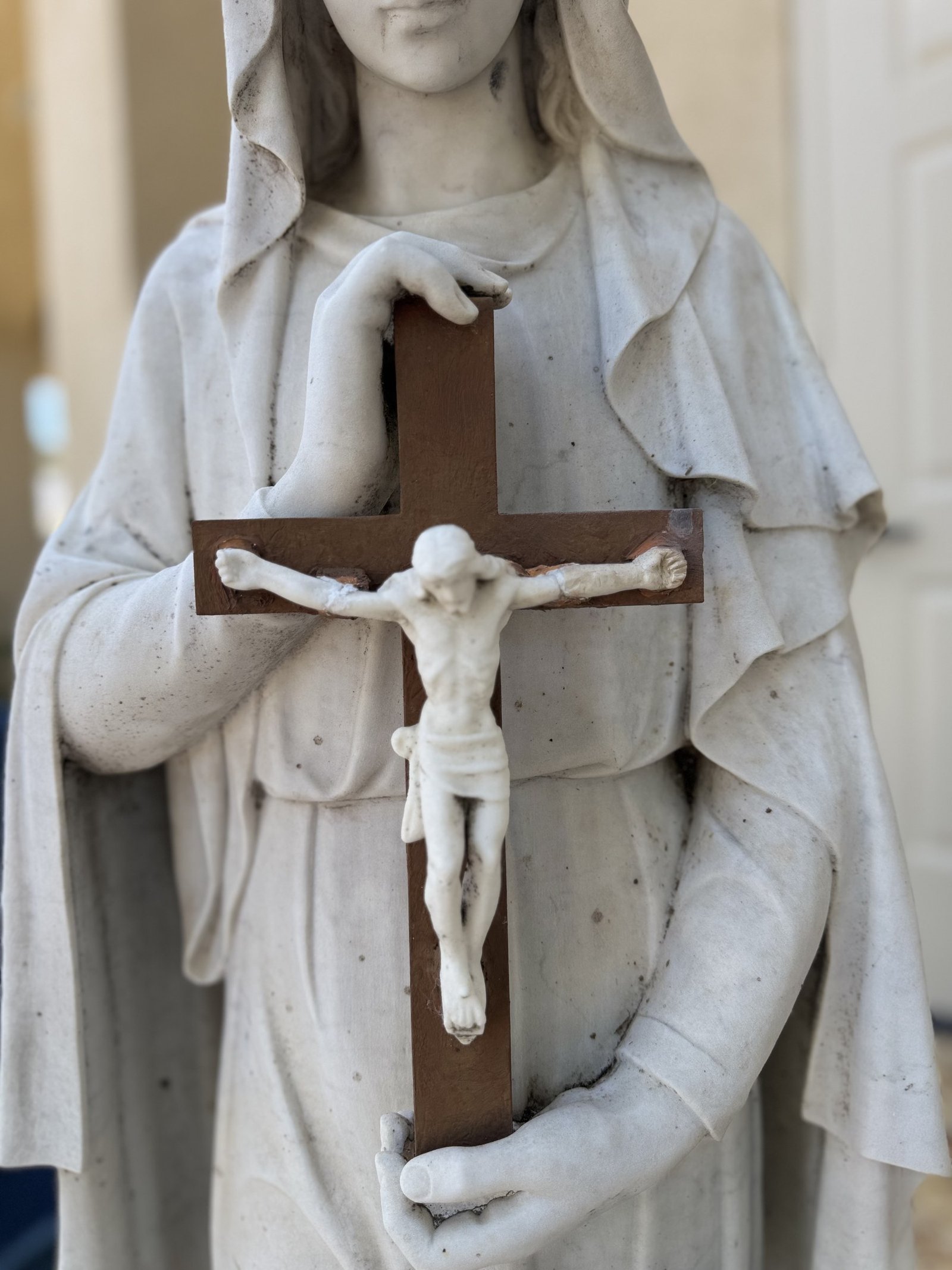 Close view of Mary's hands, the crucifix and dark marks on the statue before restoration.