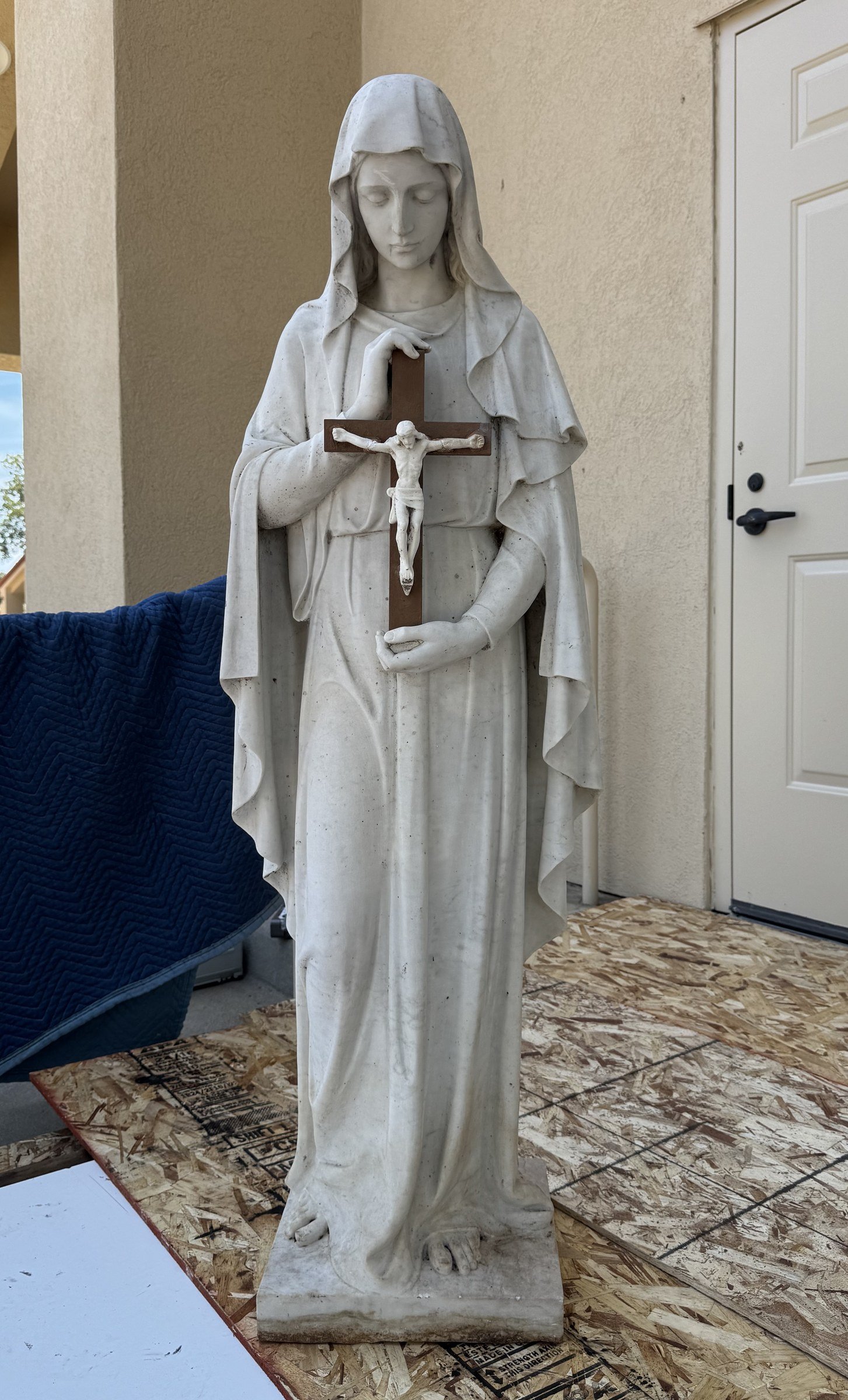 Full-length statue of Mary holding a crucifix before restoration.