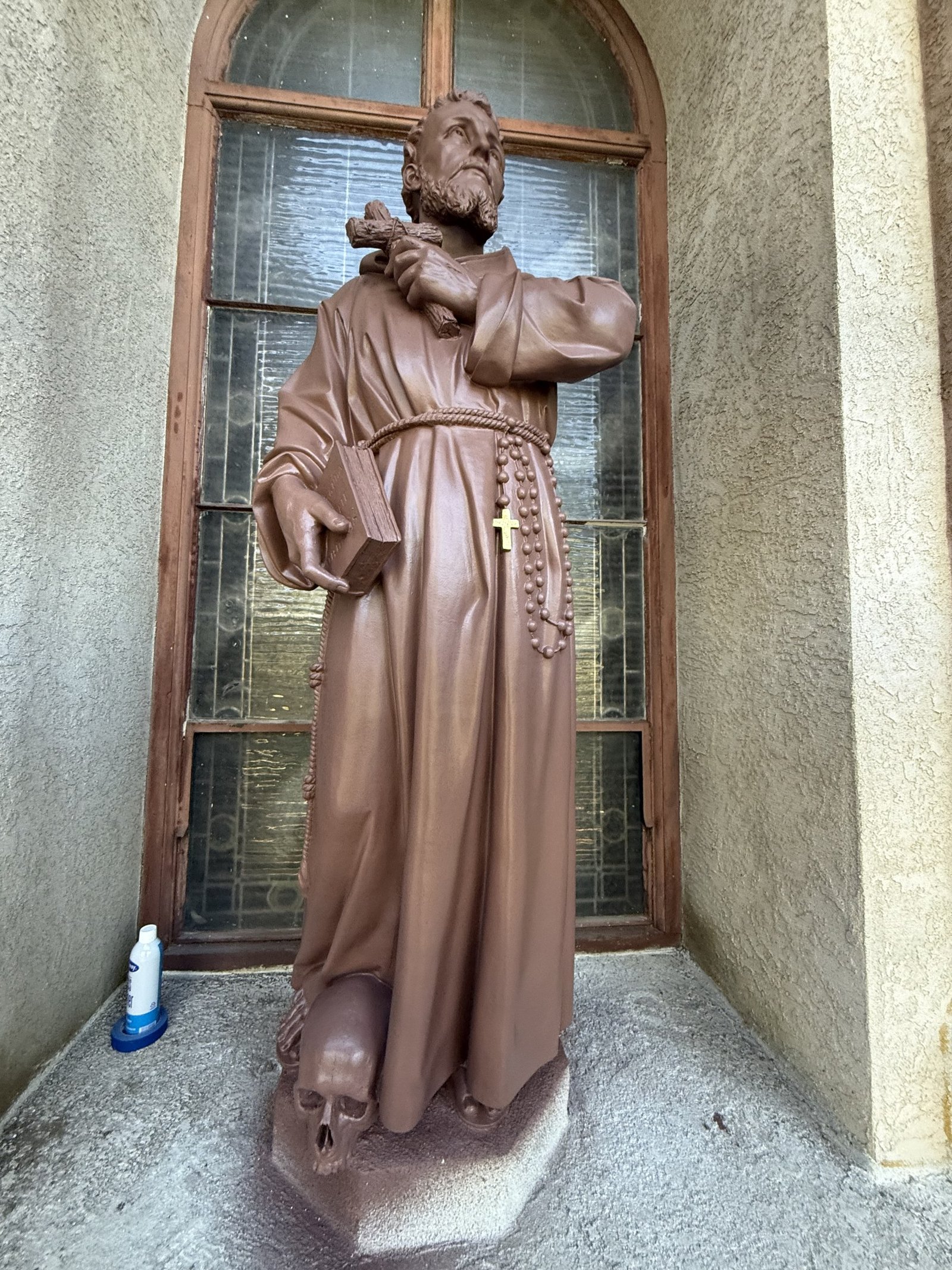 Restored terracotta statue in front of an arched church window.
