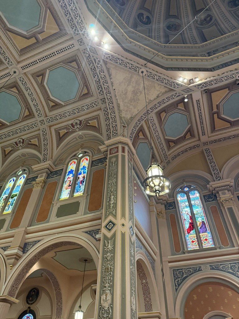 Unpainted triangular ceiling area above the column where a canvas mural is missing.