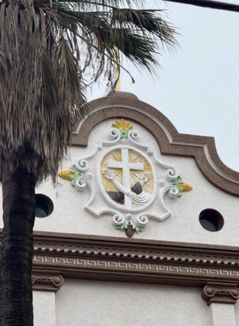 Repainted facade crest with a gold-colored cross, white scrollwork and green details.