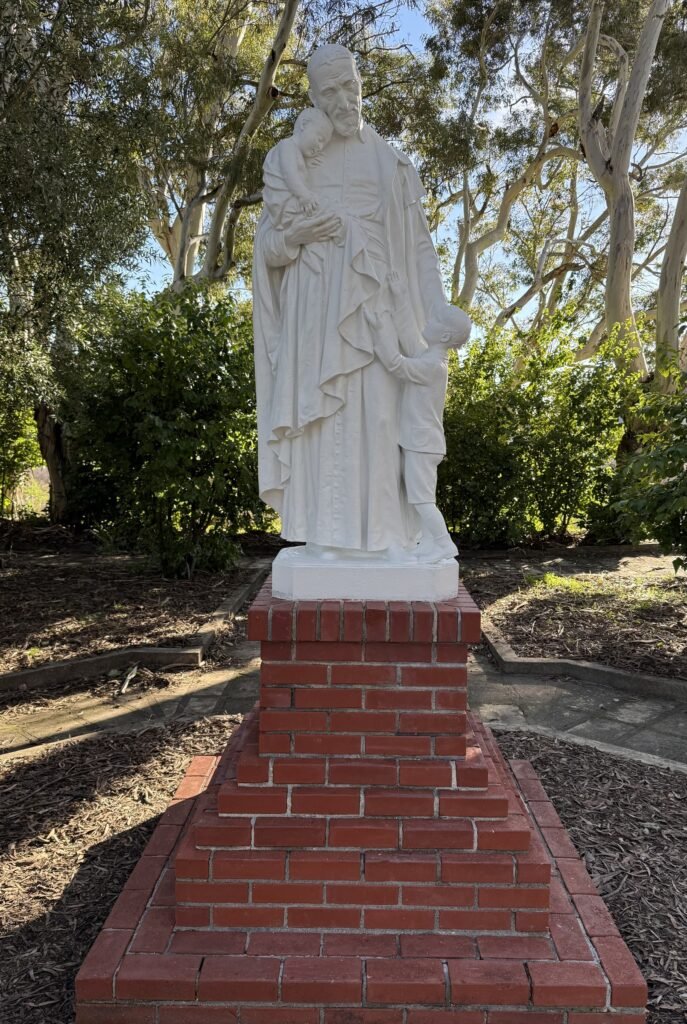 Restored standing group with two children on a brick pedestal among trees.