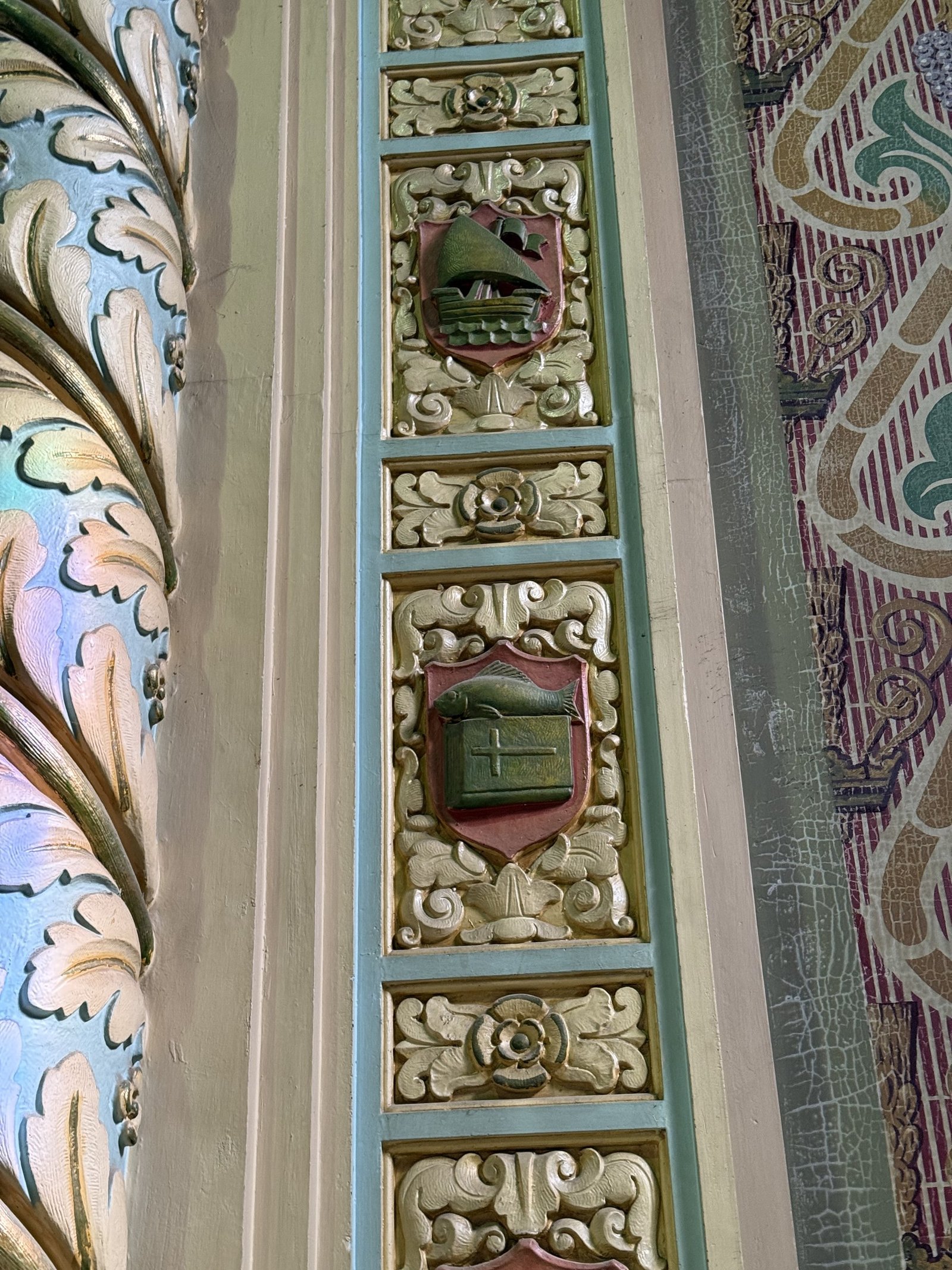 Reredos relief panels beside a blue-and-gold column and cracked painted wall pattern.
