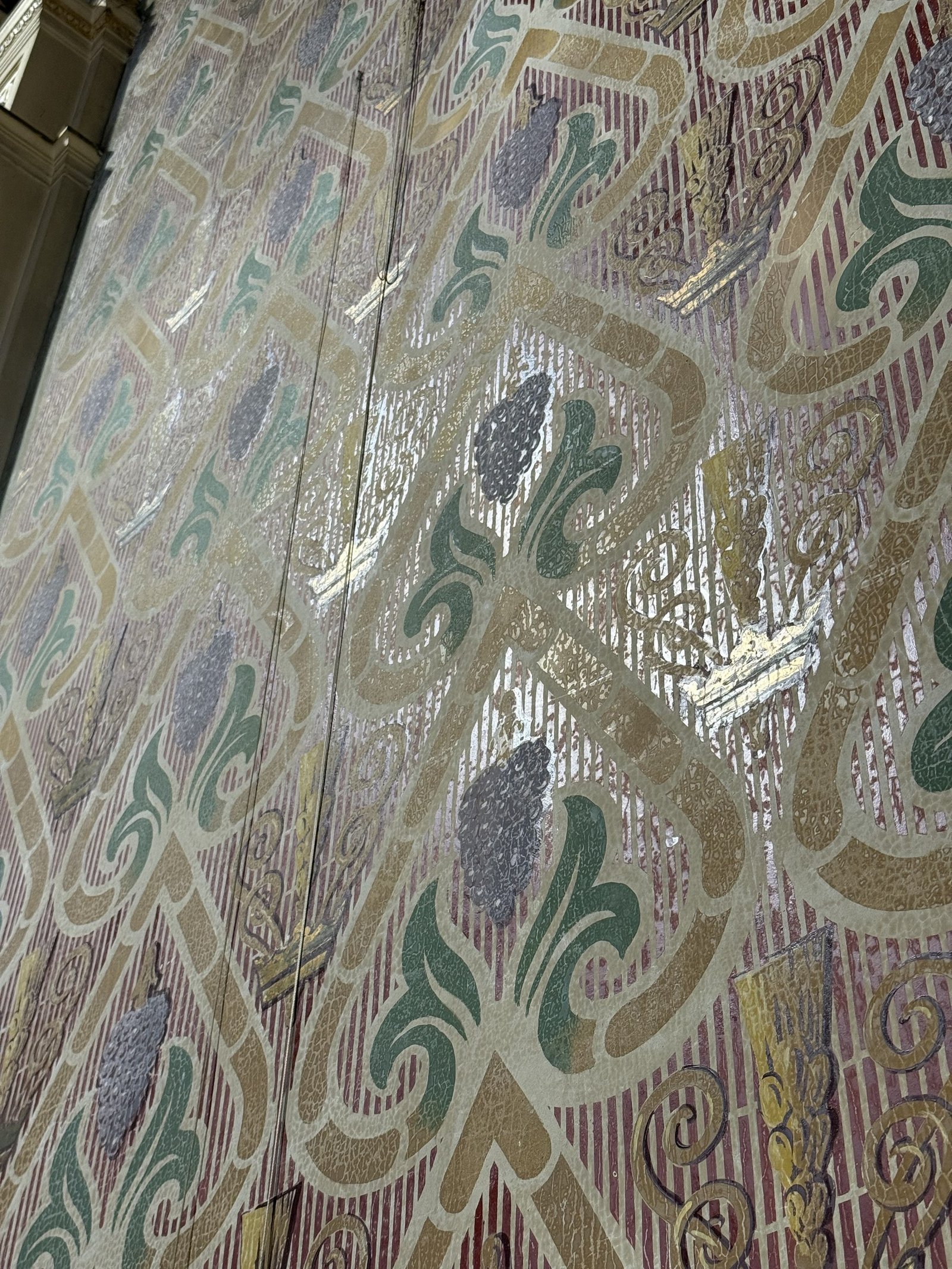 Oblique view of widespread flaking in a painted wall pattern of grapes and grain.