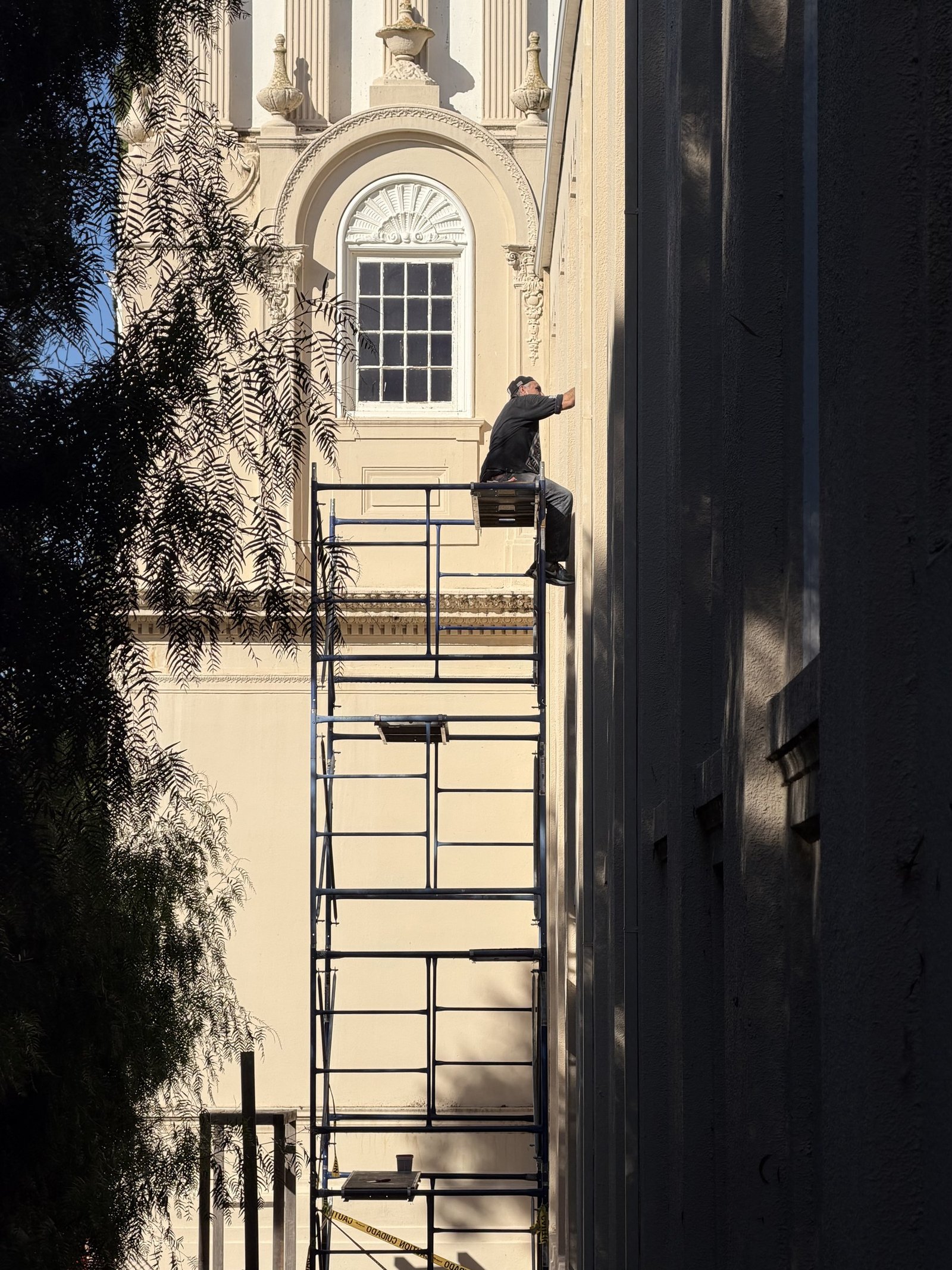 Worker on a tall scaffold platform beside the exterior church wall