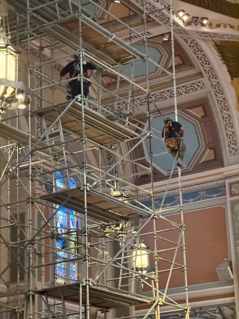 Workers on the upper levels of a scaffold tower inside the cathedral.
