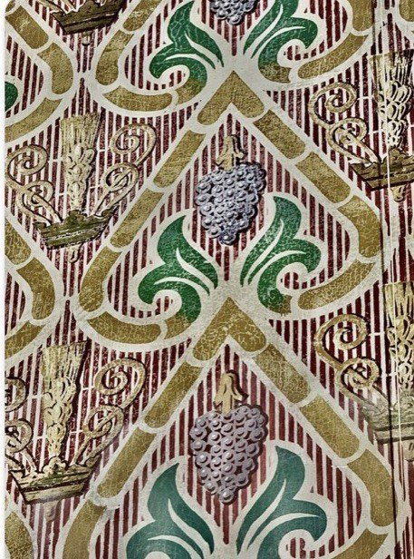 Close view of flaking paint in the repeating grape and grain wall pattern.