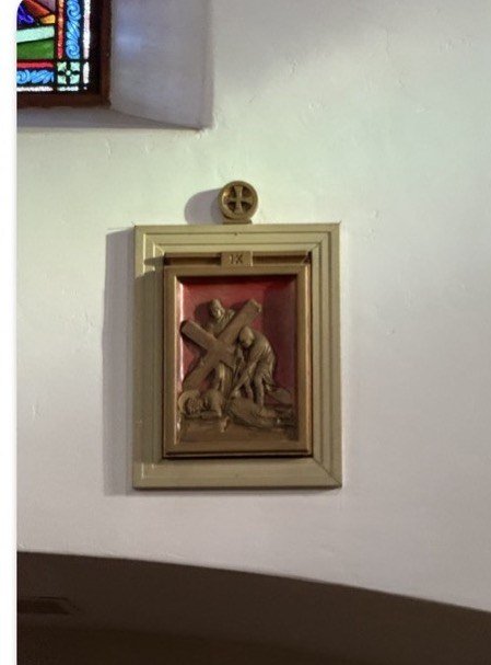 Station IX relief in a pale frame against a white church wall.