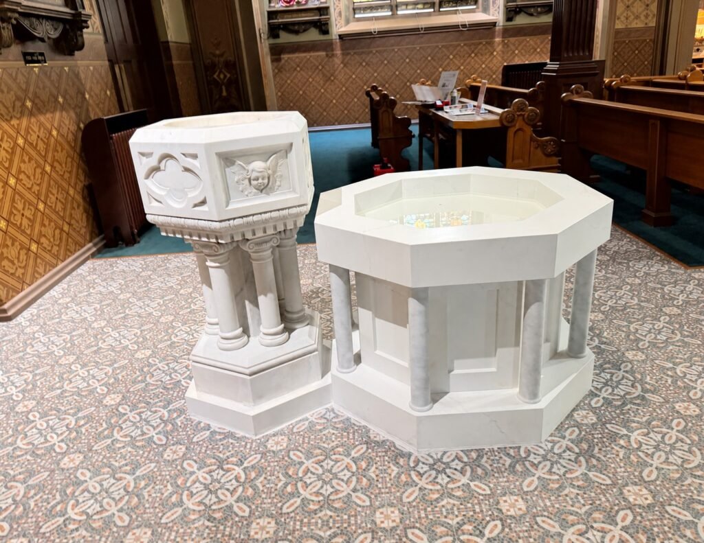 Completed font arrangement with the restored historic pedestal font beside the new octagonal marble basin.