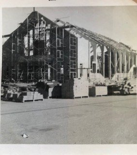 Archival street view of the church roof and wall framing during construction.